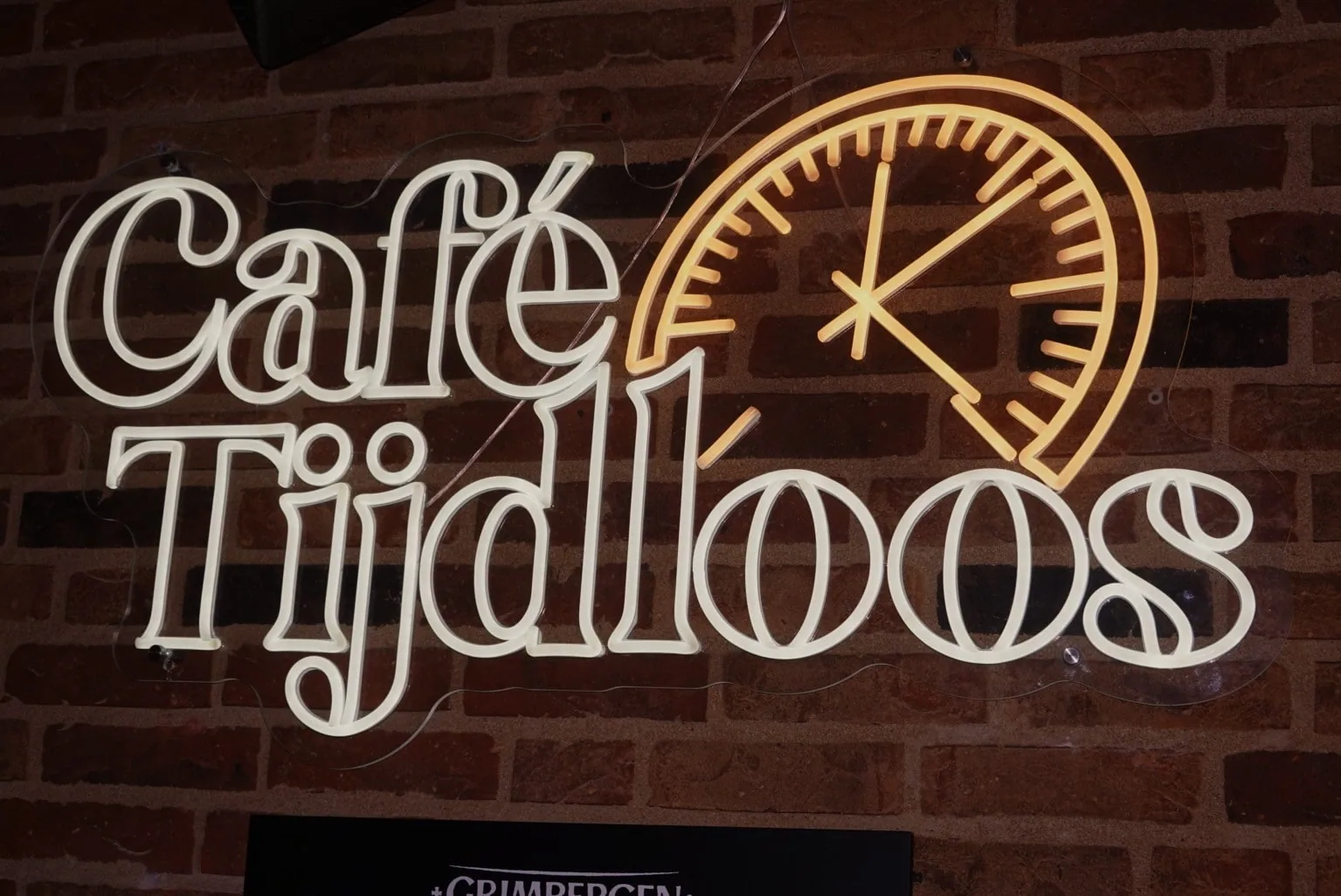 Het neonlogo van Café Tijdloos op de bakstenen muur